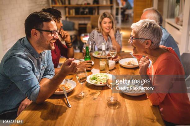 mother and son chatting during dinner party - dinner party stock pictures, royalty-free photos & images