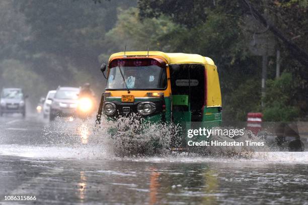 An auto-rickshaw splashes water as it passes through a waterlogged road after heavy rainfall near IIT on January 22, 2019 in New Delhi, India. Heavy...