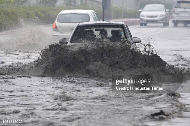 Car splashes water as it moves on a waterlogged road after the rain, at Sector 44 on January 22, 2019 in Noida, India. Heavy rains lashed parts of...