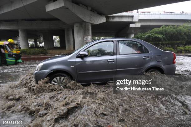 Car splashes water as it moves on a waterlogged road after the rain, at Sector 44 on January 22, 2019 in Noida, India. Heavy rains lashed parts of...