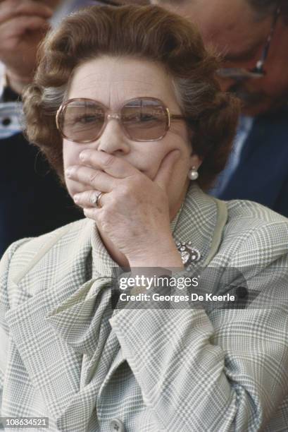 Queen Elizabeth II covering her mouth with her hand, circa 1980.