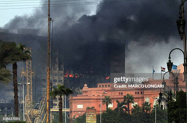 Smoke billows from a building adjacent to the Egyptian museum in the central Tahrir square in Cairo on January 29, 2011 as thousands of anti-regime...