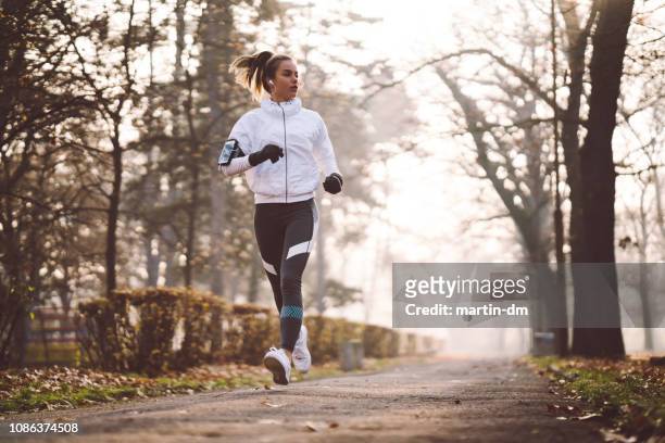 frau im winter morgens joggen - winter sport stock-fotos und bilder