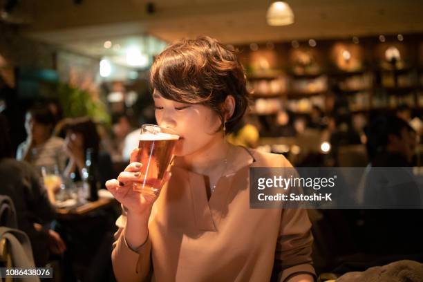 jonge vrouw drinken van een glas bier - beer drinking stockfoto's en -beelden