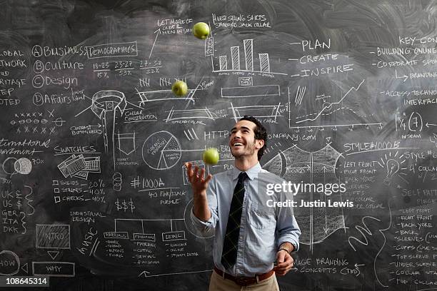 young male in front of chalkboard juggling apples - juggling stock pictures, royalty-free photos & images