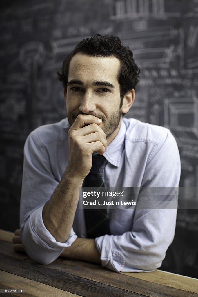 Young bussiness man smiling with chalkboard behind