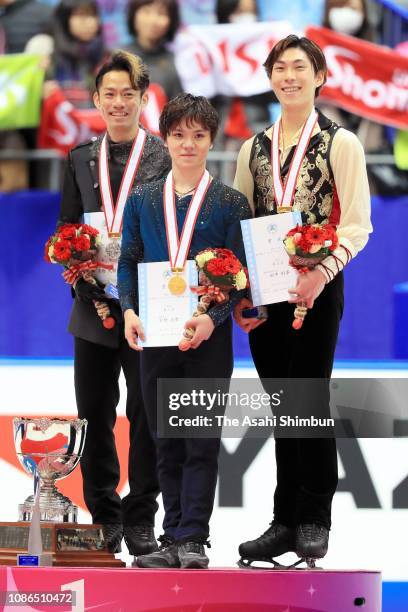 Silver medalist Daisuke Takahashi, gold medalist Shoma Uno and bronze medalist Keiji Tanaka pose on the podium at the medal ceremony for the men's...