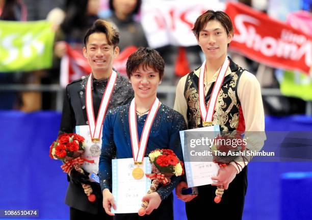 Silver medalist Daisuke Takahashi, gold medalist Shoma Uno and bronze medalist Keiji Tanaka pose on the podium at the medal ceremony for the men's...
