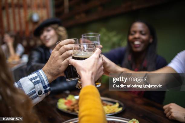 friends toasting with beer - crowded restaurant stock pictures, royalty-free photos & images