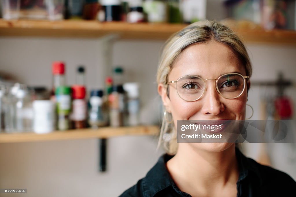 Portrait of smiling woman standing in kitchen at home