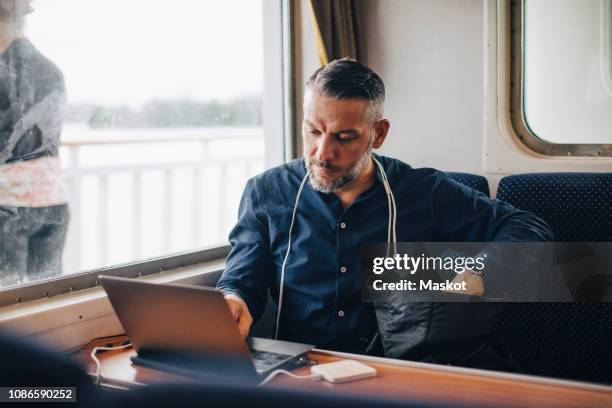 confident male entrepreneur using laptop by window while traveling in ferry - ferry stock-fotos und bilder