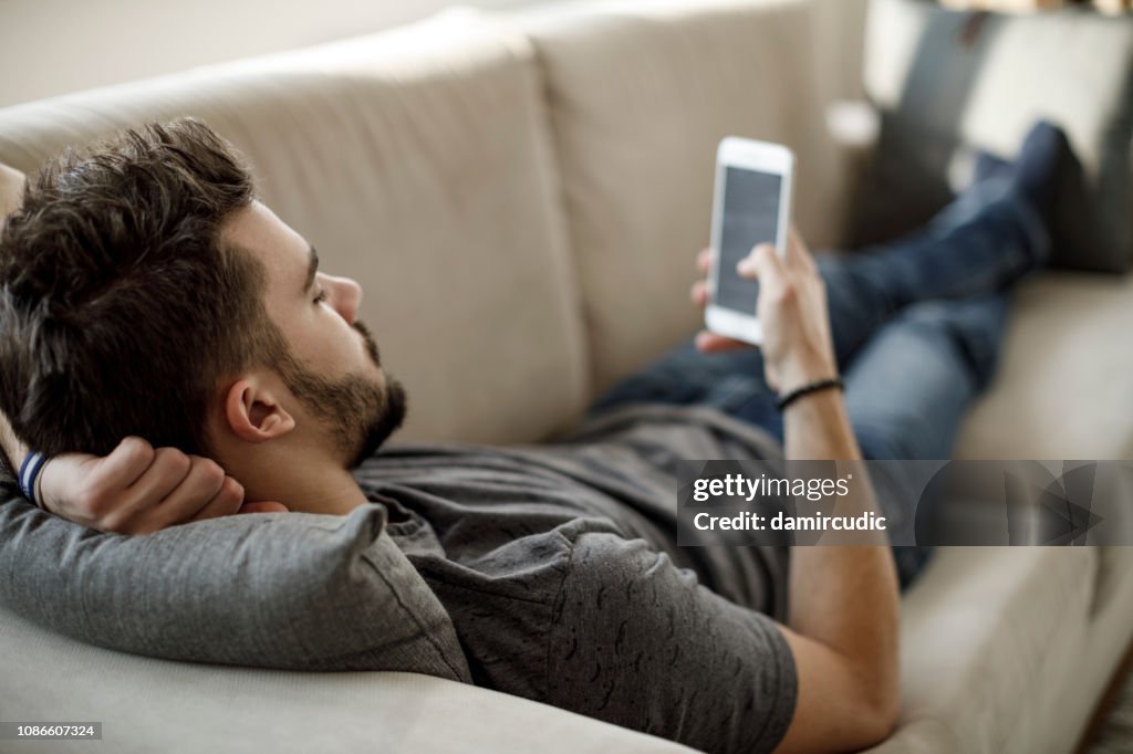 Young man using mobile phone at home