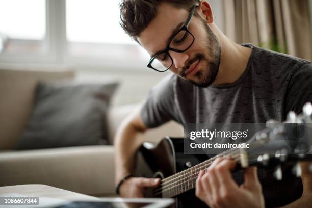 junger mann spielt zu hause gitarre - boy singing stock-fotos und bilder