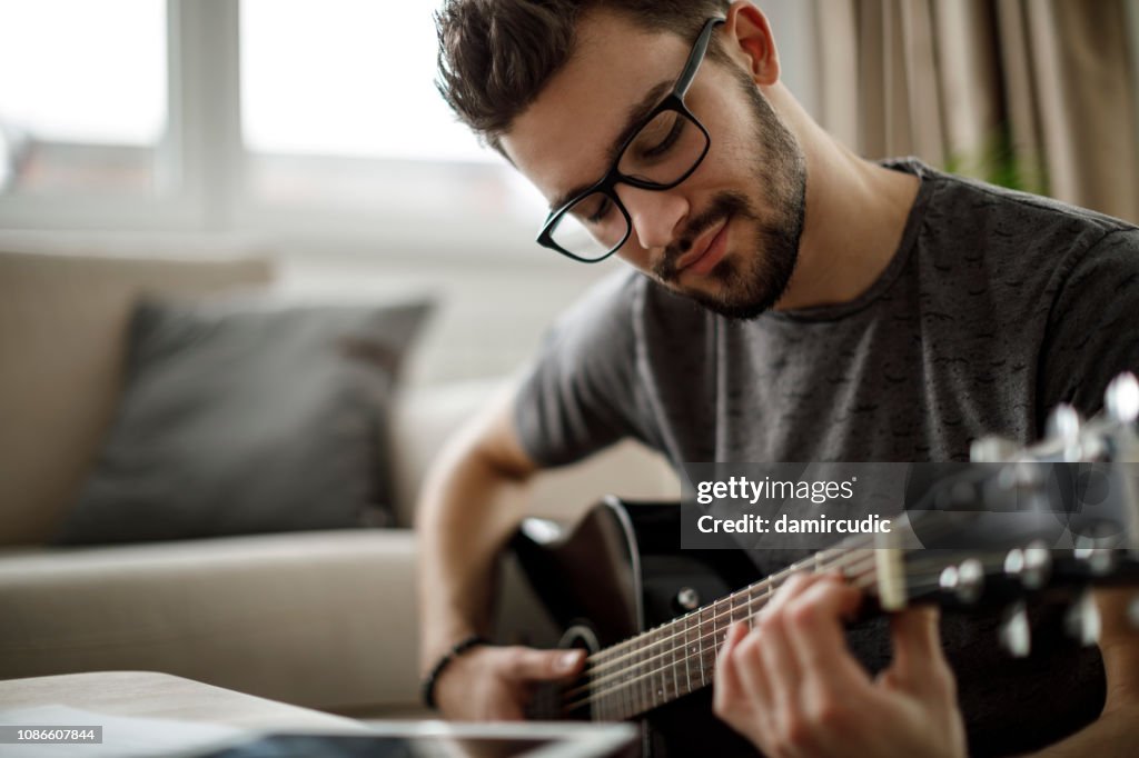 Young man playing a guitar at home