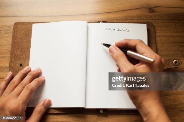 a leather-bound note pad with a short phrase "2019 goals" written on it - mann liste stock-fotos und bilder