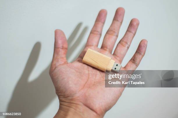 close-up of a hand holding a usb stick - usb stick stock-fotos und bilder