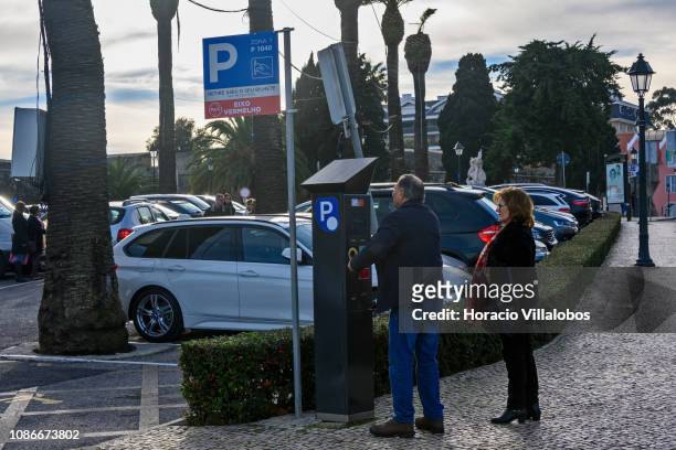 Couple gets a ticket from the parking meter near the citadel by Avenida de Dom Carlos I during Christmas afternoon on December 25, 2018 in Cascais,...