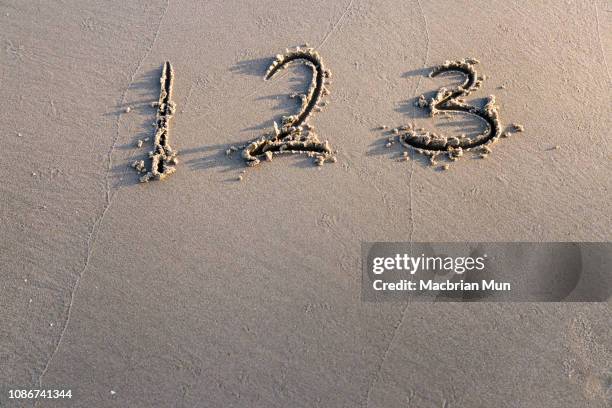 the numbers 123 written on sand - kota kinabalu beach stock pictures, royalty-free photos & images