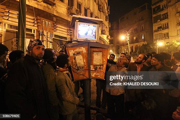 Egyptians gather to watch the Al-Jazeera satellite television station on a set placed on top of public telephone booths in Cairo's Tahrir Square,...
