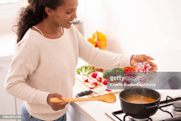 woman adding chopped radish to the boiling stock, cooking vegetable soup. - sprinkling stock pictures, royalty-free photos & images
