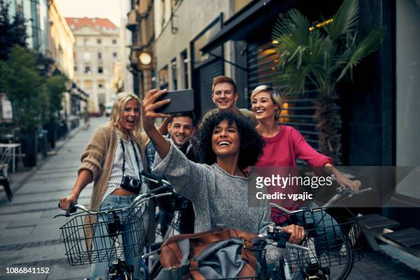 freunde auf fahrrädern in einer stadt - freundschaft stock-fotos und bilder