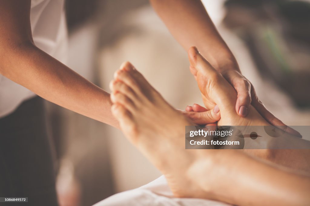 Reflexologist applying pressure to foot with thumbs