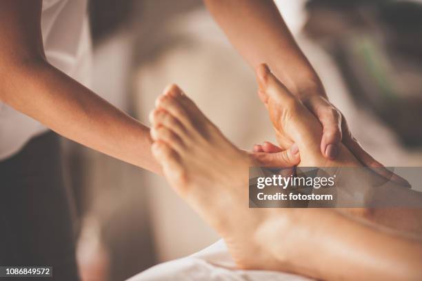 reflexologist applying pressure to foot with thumbs - foot spa stock pictures, royalty-free photos & images