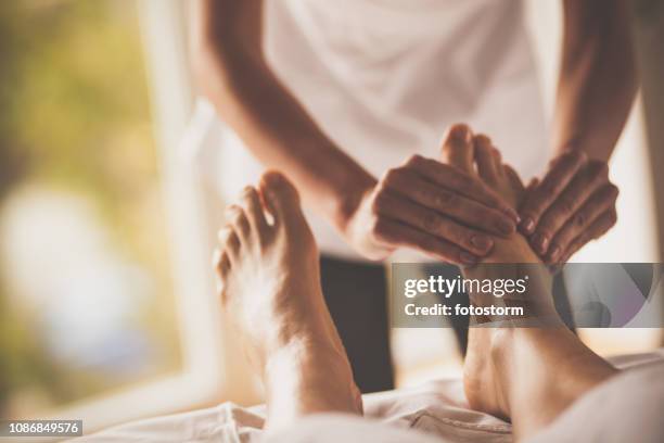 massage therapist doing foot massage at spa - reflexology stock pictures, royalty-free photos & images