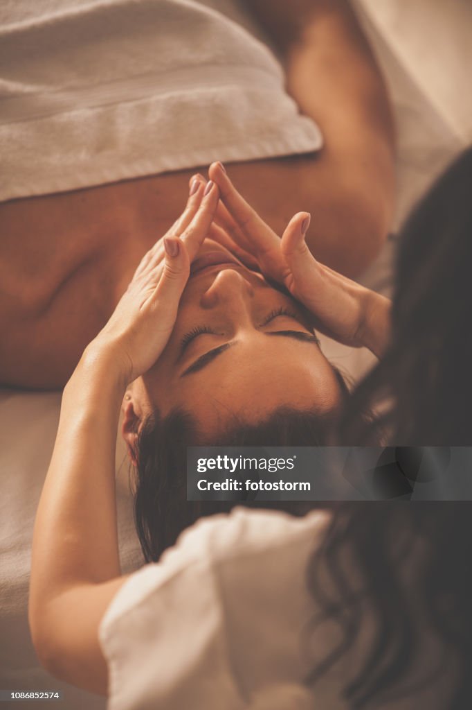 Woman enjoying facial massage at spa
