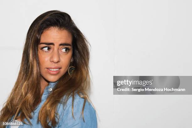 one young hispanic woman looking away from the camera on a white background - mexico city, mexico - moue de dédain photos et images de collection