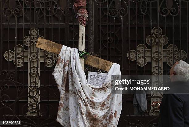 An Egyptian man stands on January 2, 2011 next to a blood-stained piece of cloth hung outside the Al-Qiddisine church in the Mediterranean port city...