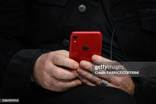 Irish rock band U2 singer Bono's hands hold is "Red" iphone during a session pannel at the World Economic Forum annual meeting, on January 23, 2019...