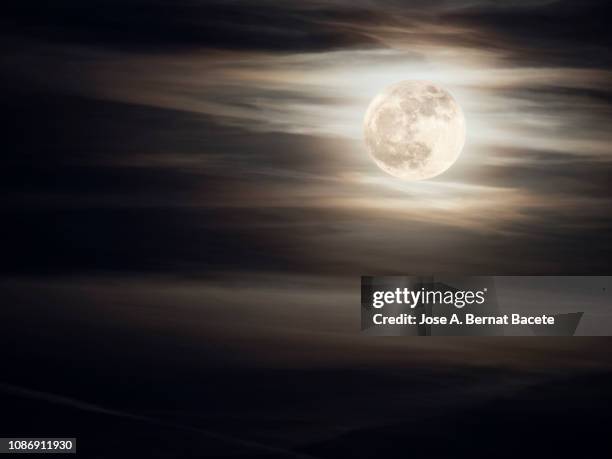 full frame of the full moon of yellow color on a sky with some high clouds (winter solstice). - moody sky moon night stock pictures, royalty-free photos & images