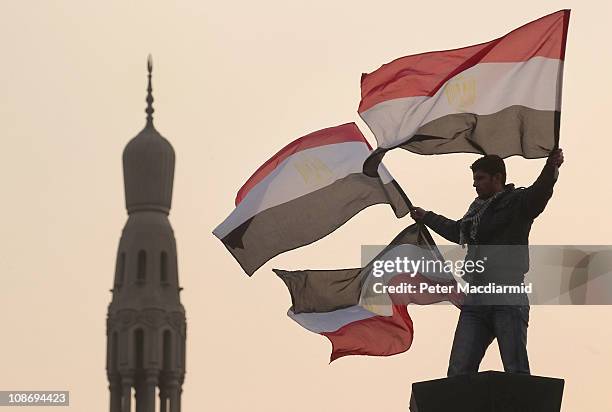 Youth waves Egyptian flags from a lamp post in Tahrir Square on February 1, 2011 in Cairo, Egypt. The Egyptian army has said it will not fire on...