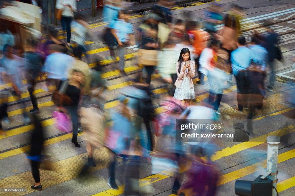 Businesswoman using mobile phone amidst crowd