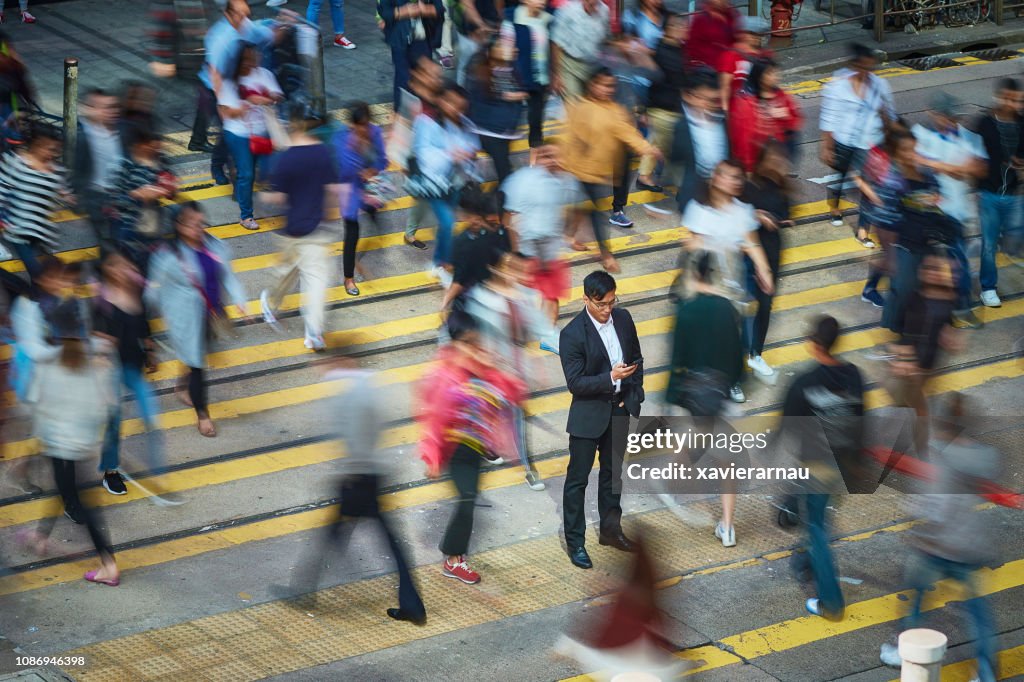 Businessman using smart phone amidst crowd