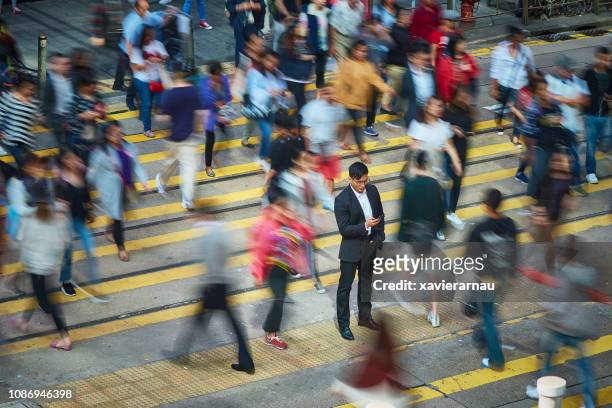 affärsman med hjälp av smart telefon mitt i folkmassan - crowd in the street bildbanksfoton och bilder