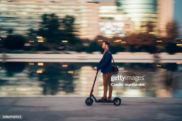 empresário, montando uma scooter na cidade - in movimento - fotografias e filmes do acervo