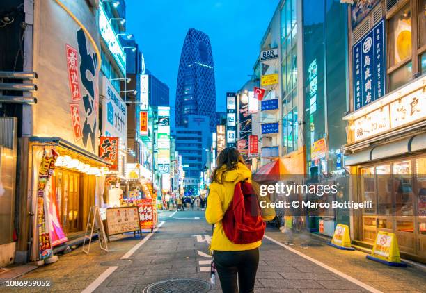 tourist walking in shinjuku at dusk, tokyo, japan - japan tourist stock pictures, royalty-free photos & images