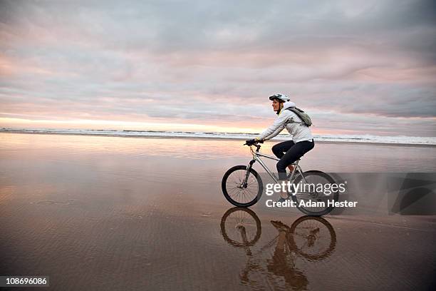 a young women riding her bike on the beach. - beach bike stock pictures, royalty-free photos & images