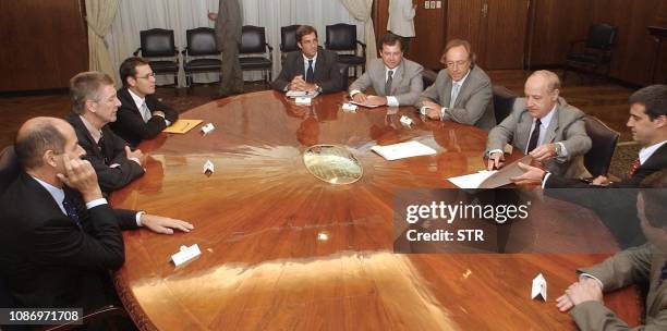 Economy Minister Roberto Lavagna signs a document next to the Secretary of Finance Guillermo Nielsen as IMF members John Dodsworth and John Thornton...