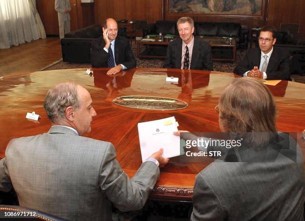 Economy Minister Roberto Lavagna hands a document to the Secretary of Finance Guillermo Nielsen as IMF members John Dodsworth and John Thornton...