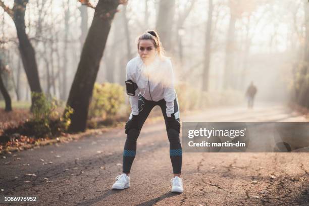 sportvrouw nemen een adem na het joggen - runner tired stockfoto's en -beelden