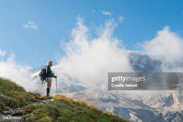 senior men hiking the hill opposite the mt. marmolada - senior adventure stock pictures, royalty-free photos & images