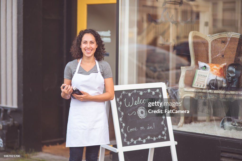 Female business owner stands on the sidewalk outside her salon