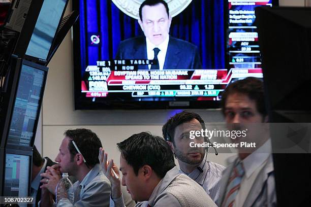 With a television screen showing images of Egyption president Hosni Murbark, traders work on the floor of the New York Stock Exchange at the end of...