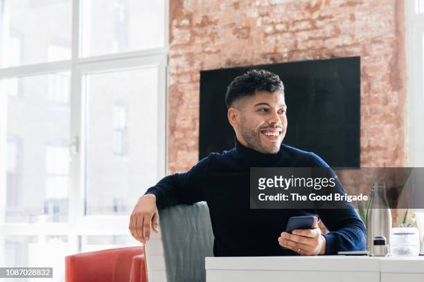 smiling businessman with mobile phone looking away - turtleneck stock pictures, royalty-free photos & images