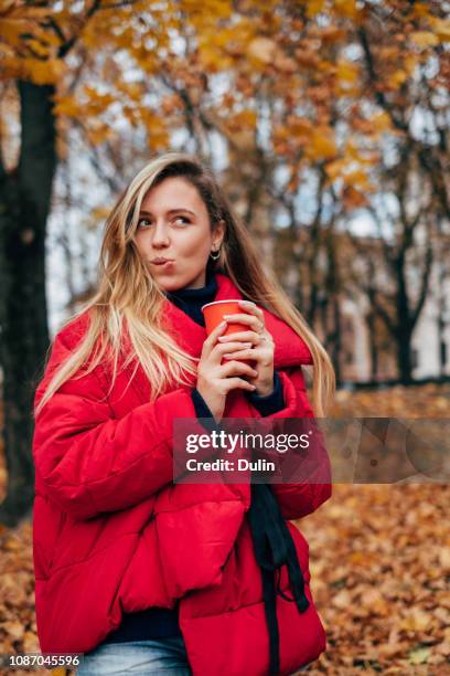 woman standing in a park with a hot drink, belarus - down coat stock pictures, royalty-free photos & images