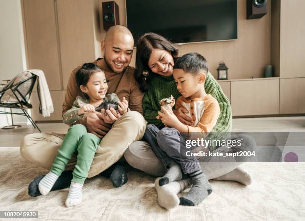 family sitting in the living on the floor - family four people stock pictures, royalty-free photos & images