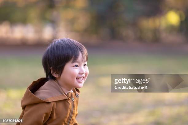 喜びと公共の公園で走っている小さな少年 - 少年 ストックフォトと画像